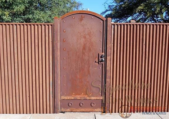 Sheet Steel Gate | Affordable Fence & Gates | Signature Ironworks | Corrugated Steel Gate | Rusty Corrugated Steel Gate | Natural Rust Corrugated Steel Gate | Arch | Rivets | Clevos | Handle | Court Yard Gate | Flower Detail | Natural Rust Color