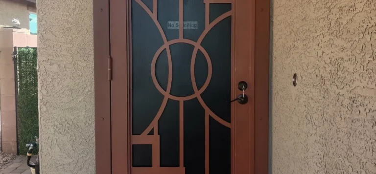 A brownish security door with circular patterns in the center and square designs in the corners, all set against a black mesh screen.